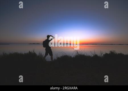 Silhouette d'homme regardant le lever du soleil dans la Mar Menor, Cartagena Banque D'Images