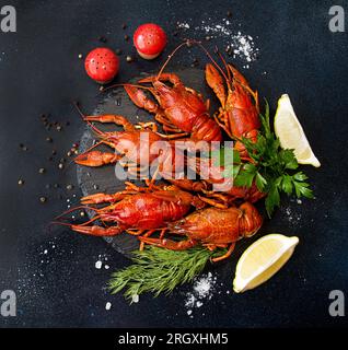 Écrevisses cuites bouillies prêtes à manger sur une planche à découper blanche sur fond bleu foncé noir. Frais généraux. Banque D'Images