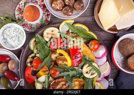 Set collection de fromages et de collations. Halloumi grillé, knolle belper, olives, sauce tzatziki sur fond rustique en bois ancien. Frais généraux. Banque D'Images