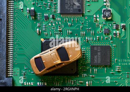 Voitures jouets sur carte électronique et puce électronique. Image conceptuelle de la pénurie de semi-conducteurs perturbant la production de l'industrie automobile. Banque D'Images