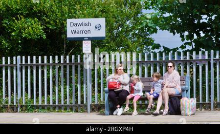 Deux femmes et deux enfants sont assis sur un banc sur le quai attendant un train à Dawlish Warren. Banque D'Images