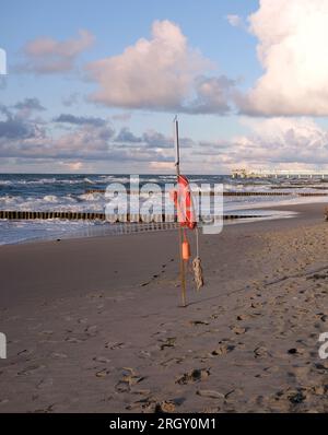 Gilet de sauvetage sur le stand sur la plage de sable vide près des vagues de mer d'assaut Banque D'Images