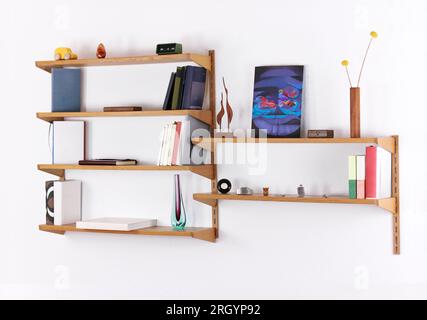 Une bibliothèque d'occasion du milieu du siècle originale des années 60 montée sur un mur blanc. Rempli de livres et autres accessoires rares dans le design scandinave deuxième Banque D'Images