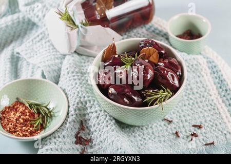 Prunes marinées aux épices dans un pot en verre sur la table de cuisine Banque D'Images