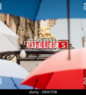 Gros plan de l'enseigne du pub Fuller's Griffin Brewery au milieu de parapluies colorés rouges, blancs et bleus sur Church court, Richmond, Angleterre, Surrey, Royaume-Uni Banque D'Images