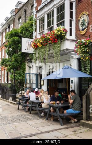 Les gens assis et prenant un verre devant la maison publique Cricketers sur Richmond Green, Richmond, TW9, Surrey, Angleterre, ROYAUME-UNI Banque D'Images