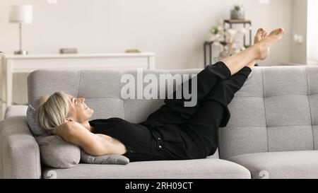 Heureuse femme d'âge moyen détendue allongée sur un canapé confortable Banque D'Images