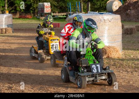 Trois pilotes de tondeuse à gazon de course se bousculent pour une position dans la BLMRA 500, une course de tondeuse à gazon de nuit de 500 miles dans le style du Mans dans un champ du West Sussex, au Royaume-Uni. La British Lawn Mower Racing Association organise son 50e anniversaire de course de 12 heures dans la nuit samedi/dimanche avec 52 équipes, chacune avec trois pilotes. Banque D'Images