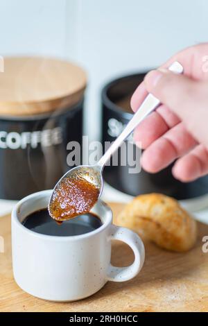 Les grains de cassonade aspirent le café chaud,faisant dans une texture sirupeuse,avant d'être remué dans un espresso noir fraîchement infusé,prêt à boire,chaud Banque D'Images