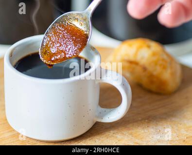 Les grains de cassonade aspirent le café chaud,faisant dans une texture sirupeuse,avant d'être remué dans un espresso noir fraîchement infusé,prêt à boire,chaud Banque D'Images