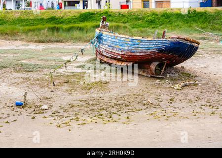 Un vieux bateau en bois délabré s'est échoué à marée basse sur les rives de la rivière Rother à Rye Harbour, un petit village côtier du Sussex de l'est près de la ville de Rye Banque D'Images