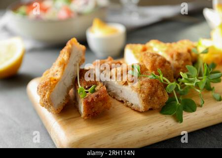 Délicieux schnitzel coupé servi avec des microgreens sur la table grise, gros plan Banque D'Images