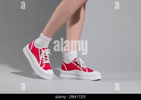 Femme portant des baskets Old School classiques rouges sur fond gris clair, gros plan Banque D'Images