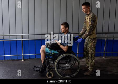 Des bénévoles de l'organisation paramédicale hospitalière déplacent un soldat ukrainien blessé vers un bus médical spécial pendant l'évacuation. Les hospitaliers sont un bataillon magique de volontaires ukrainiens qui fournit les premiers soins et évacue les soldats ukrainiens blessés de la zone de guerre depuis 2014. Le bus médicalement équipé des hospitaliers - nommé «autrichien», le surnom d'un ambulancier paramédical hospitalier qui a été tué dans un accident d'un autre bus d'évacuation médicale - peut transporter six patients gravement blessés sur des civières, et plusieurs autres blessés à pied. Banque D'Images