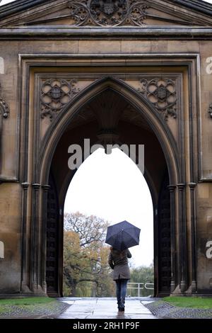 Femme sous parapluie marchant dans les rues de Cambridge Banque D'Images