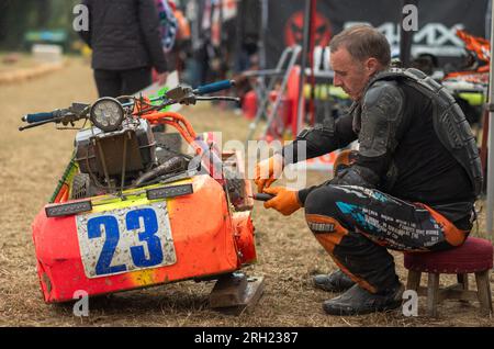 Billingshurst, West Sussex, Royaume-Uni. 12 août 2023. Un conducteur de tondeuse à gazon de course répare sa tondeuse dans la voie des stands à l'aube lors de la BLMRA 500, une course de tondeuse à gazon de nuit de 500 miles dans le style du Mans dans un champ du West Sussex, au Royaume-Uni. La British Lawn Mower Racing Association organise son 50e anniversaire de course de 12 heures dans la nuit samedi/dimanche avec 52 équipes, chacune avec jusqu'à trois pilotes. Crédit : Andy Soloman/Alamy Live News Banque D'Images