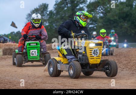 Billingshurst, West Sussex, Royaume-Uni. 12 août 2023. Les pilotes de tondeuse à gazon de course se bousculent alors qu'ils prennent un virage à l'aube dans la BLMRA 500, une course de tondeuse à gazon d'endurance de 500 miles dans le style du Mans dans un champ du West Sussex, au Royaume-Uni. La British Lawn Mower Racing Association organise son 50e anniversaire de course de 12 heures dans la nuit samedi/dimanche avec 52 équipes, chacune avec jusqu'à trois pilotes. Crédit : Andy Soloman/Alamy Live News Banque D'Images