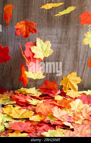 Feuilles d'automne colorées tombant sur les feuilles d'automne. Fond en bois. Prise de vue en studio. Tir vertical Banque D'Images