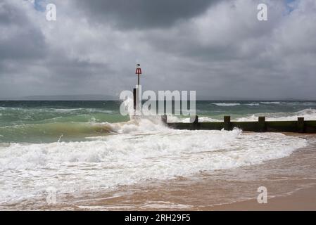 Vagues s'écrasant dans un groyne sur un jour venteux avec le ciel sombre Banque D'Images