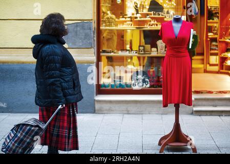 Femme âgée regardant la robe accrocheuse Banque D'Images