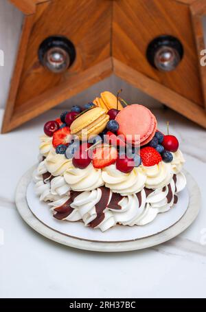 Gâteau Pavlova avec fraise, framboise, bleuberry, macarons et sauce chocolat Banque D'Images