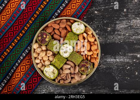 Noix mélangées. Divers noix, pistaches, amandes, délice turc et biscuits assortis sur un plateau en cuivre, vue d'en haut. Banque D'Images