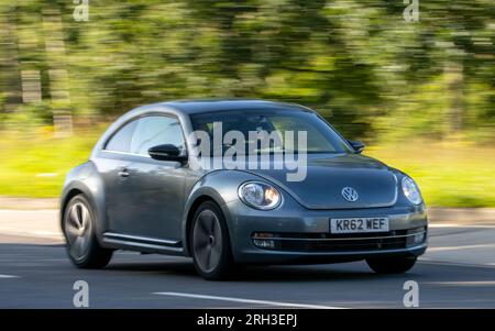 Milton Keynes, Royaume-Uni - 10 août 2023 : 2013 Volkswagen Beetle voiture conduisant sur une route de campagne anglaise. Banque D'Images