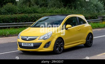 Milton Keynes, Royaume-Uni - 13 août 2023 : 2011 voiture jaune Vauxhall Corsa conduisant sur une route de campagne anglaise. Banque D'Images