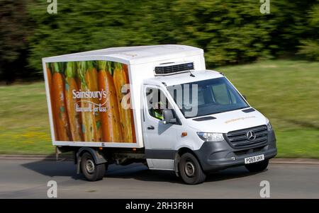 Milton Keynes, Royaume-Uni - 11 août 2023 : Mercedes Benz Sprinter utilisé comme camion de livraison Sainsbury. Conduite sur une route de campagne anglaise. Banque D'Images