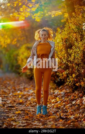 Bonjour automne. Portrait pleine longueur de femme en forme dans des vêtements de fitness dans la séance d'entraînement du parc. Banque D'Images