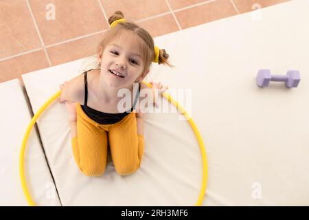 Petite fille blonde avec queues de porc jouant avec hula Hoop Banque D'Images