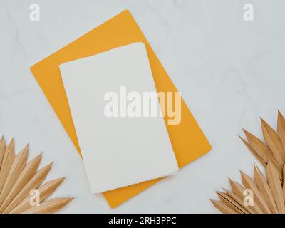 Couche plate de feuilles de palmier tropical en forme d'éventail séchées et blocs-notes jaunes et blancs sur fond blanc. Vue de dessus. Espace de copie Banque D'Images