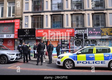 Manchester, Royaume-Uni. 13 août 2023. La police du Grand Manchester a fermé Oldham Street, dans le centre de Manchester, au Royaume-Uni, dimanche. À 16,24 h 30, un homme a été étiré hors du magasin Mini Market pour se rendre à une ambulance et emmené à l'hôpital. Un porte-parole de la police a déclaré : « cela est traité comme un incident isolé et la victime - un homme de 27 ans - a été emmenée à l'hôpital pour le traitement de blessures graves, bien que celles-ci ne soient heureusement pas considérées comme mettant la vie en danger. Une enquête est en cours et une scène a été mise en place pour faciliter les enquêtes. » Crédit : Terry Waller/Alamy Live News Banque D'Images