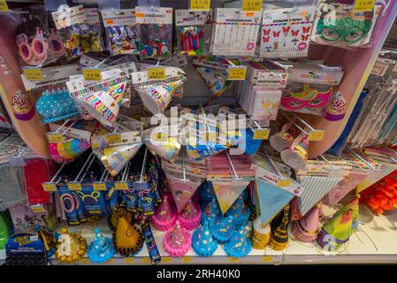 Italie - 08 août 2023 : drapeaux de fête de bandoulière en papier, chapeaux en papier de joyeux anniversaire et accessoires de fête exposés à la vente en magasin italien Banque D'Images