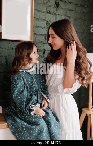 Fête des mères. Une jeune maman sensible embrasse sa petite fille adorable à la maison. Confiance, soutien et amour entre maman et enfant. Une famille aimante Banque D'Images