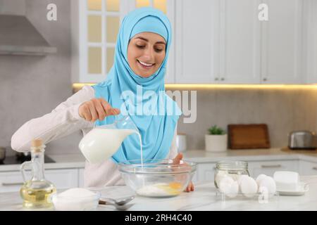 Femme musulmane faisant de la pâte à la table blanche dans la cuisine Banque D'Images