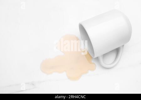 Flaque de liquide et tasse renversée sur la table en marbre blanc, vue au-dessus. Espace pour le texte Banque D'Images
