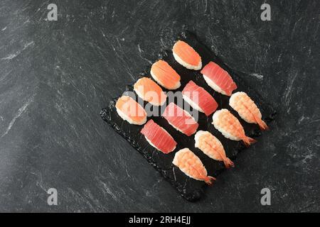 Nigiri saumon, thon et sushi aux crevettes, vue de dessus sur une table en marbre noir Banque D'Images