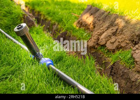 Auto-installation de l'irrigation avec un arroseur rétractable dans la pelouse finie. Pose de conduites d'eau avec des pulvérisateurs sous la pelouse pour l'irrigation. Banque D'Images