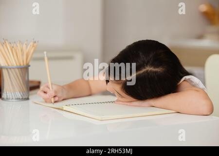 l'éducation paresseuse des filles à la maison se sent ennuyeuse assise tête en bas faire ses devoirs Banque D'Images