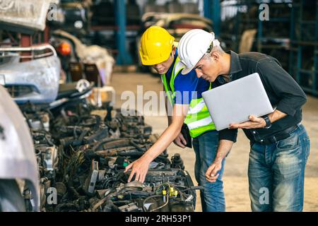 L'équipe d'ingénieurs principaux vérifie l'inventaire du magasin ancienne liste de pièces de rechange automatiques usagées de pièces de rechange de moteur pour le recyclage de vente dans le marché de garage de voiture de réparation Banque D'Images