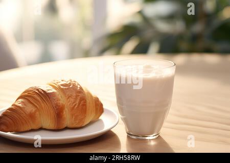 Un croissant fraîchement cuit à côté d'un verre de lait, évoquant le charme d'un petit déjeuner sucré matinal. Banque D'Images