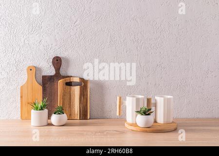 Beau fond de cuisine dans un style minimaliste avec deux tasses en céramique élégantes et un ensemble de différentes planches à découper en bois. vue avant Banque D'Images