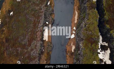 Ruisseau d'eau courant entre les champs en islande, vue aérienne de la majestueuse cascade d'oxarafoss dans le paysage islandais. Cascade nordique descendant des falaises gelées et des collines. Ralenti. Banque D'Images