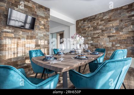 Salle à manger avec table en bois et chaises bleues au sol dans un appartement moderne. Banque D'Images