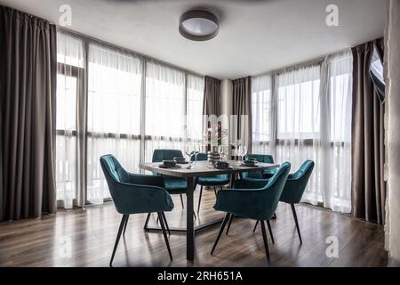 Salle à manger avec table en bois et chaises bleues au sol dans un appartement moderne. Banque D'Images