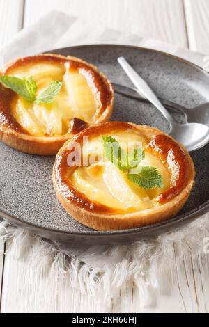 Mini tarte aux pommes avec crème anglaise et menthe gros plan dans une assiette sur la table. Vertical Banque D'Images