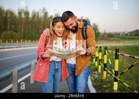 Heureux couple souriant regardent la carte dans la ville. Les touristes font du tourisme dans la ville. Banque D'Images