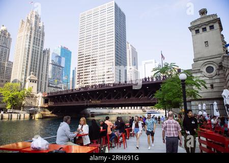 Les gens boivent et mangent près du Chicago Riverwalk près du Bataan-Corregidor Memorial Bridge avec le bâtiment Langham à l'arrière, Illinois, USA Banque D'Images