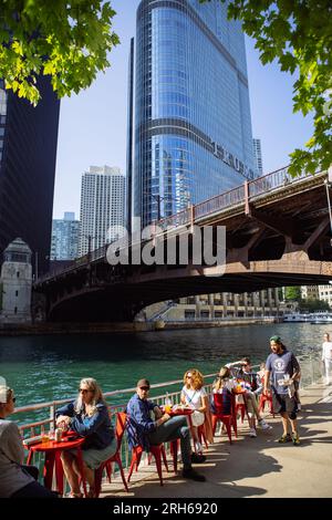 Les gens boivent et mangent près du Chicago Riverwalk près du pont Irv Kupcinet avec Trump Tower à l'arrière, Illinois, USA Banque D'Images